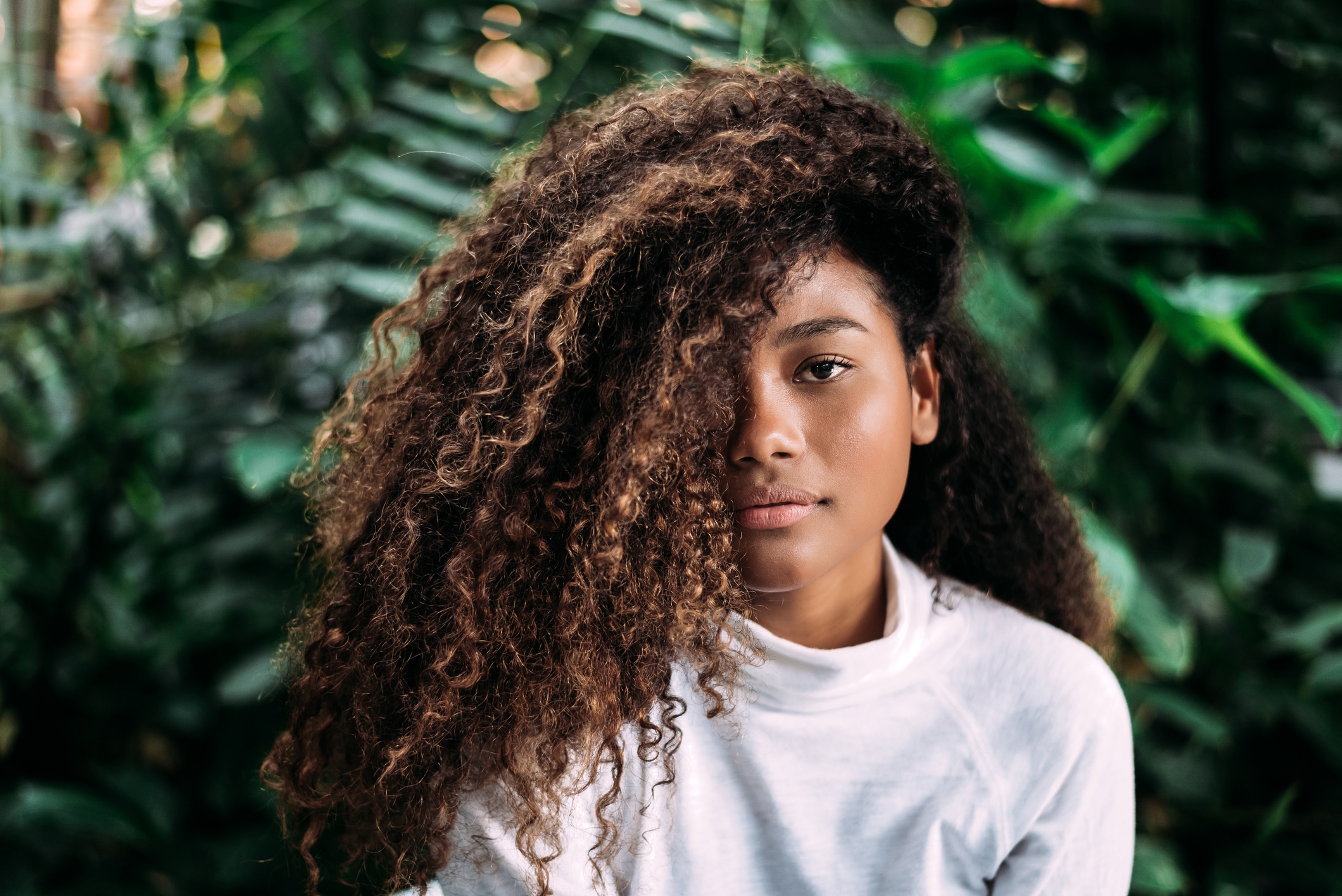  Mulher negra pensativa com cabelo cacheado na natureza