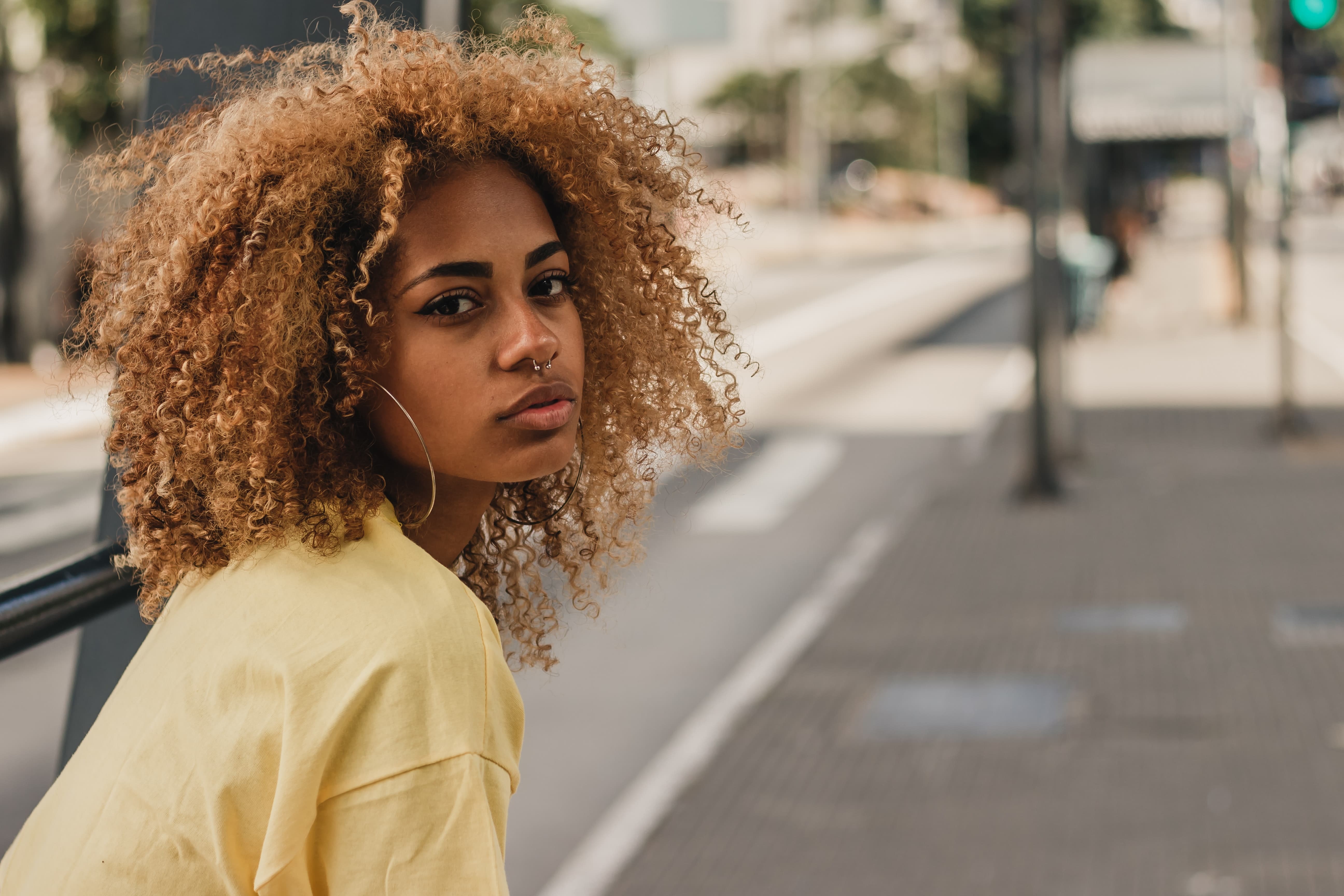  Mulher negra com cabelo cacheado e camisa amarela na rua da cidade