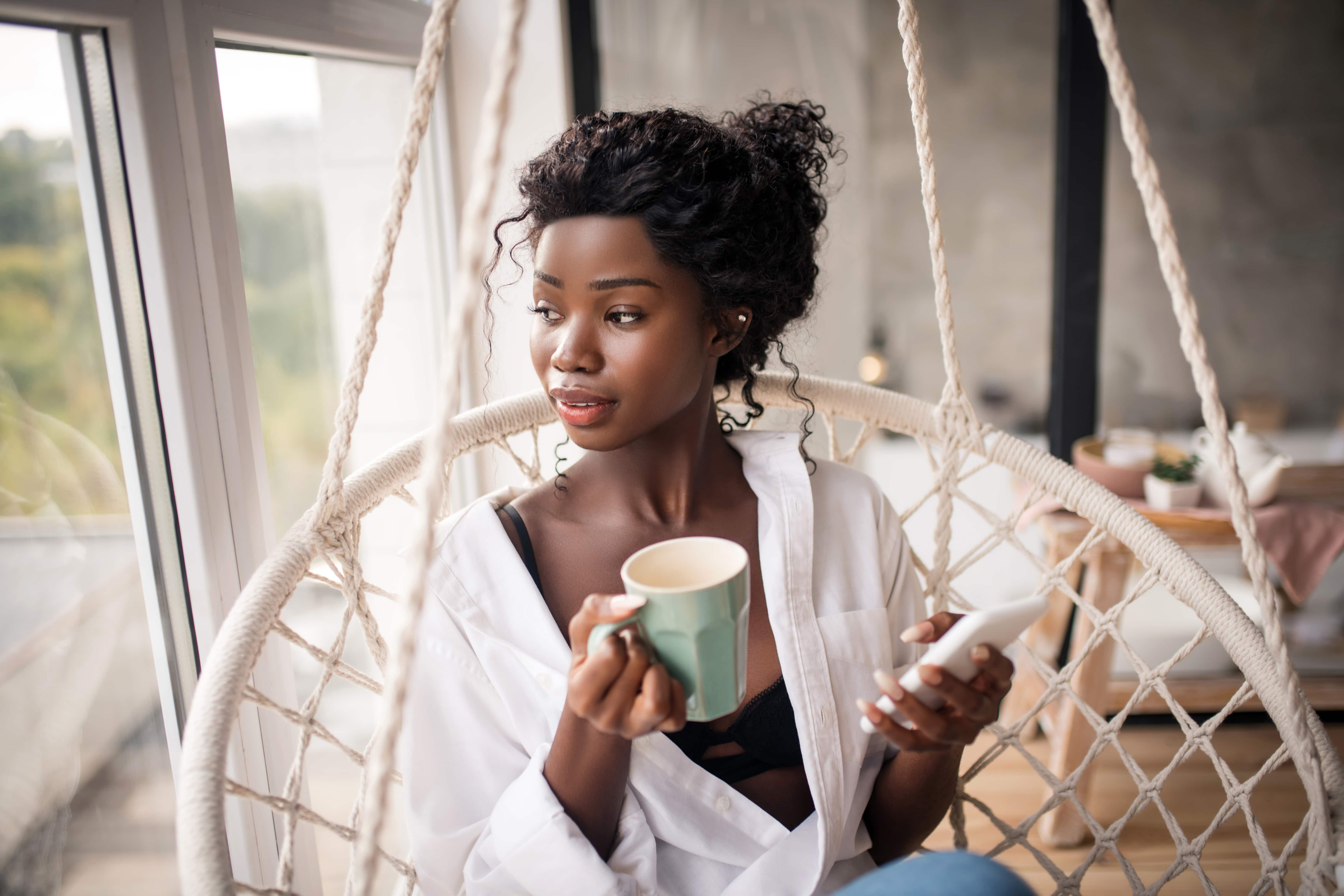  Mulher negra saboreando café em cadeira suspensa