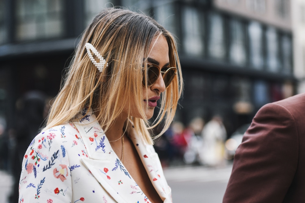  Mulher com cabelo loiro ombré e óculos escuros, detalhe de presilha de pérola