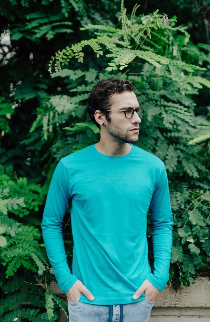 homem branco com cabelo ondulado e blusa de manga comprida azul