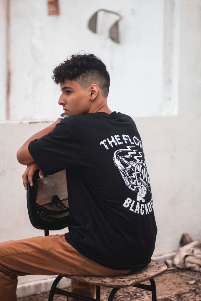 homem branco com cabelo ondulado e camiseta preta