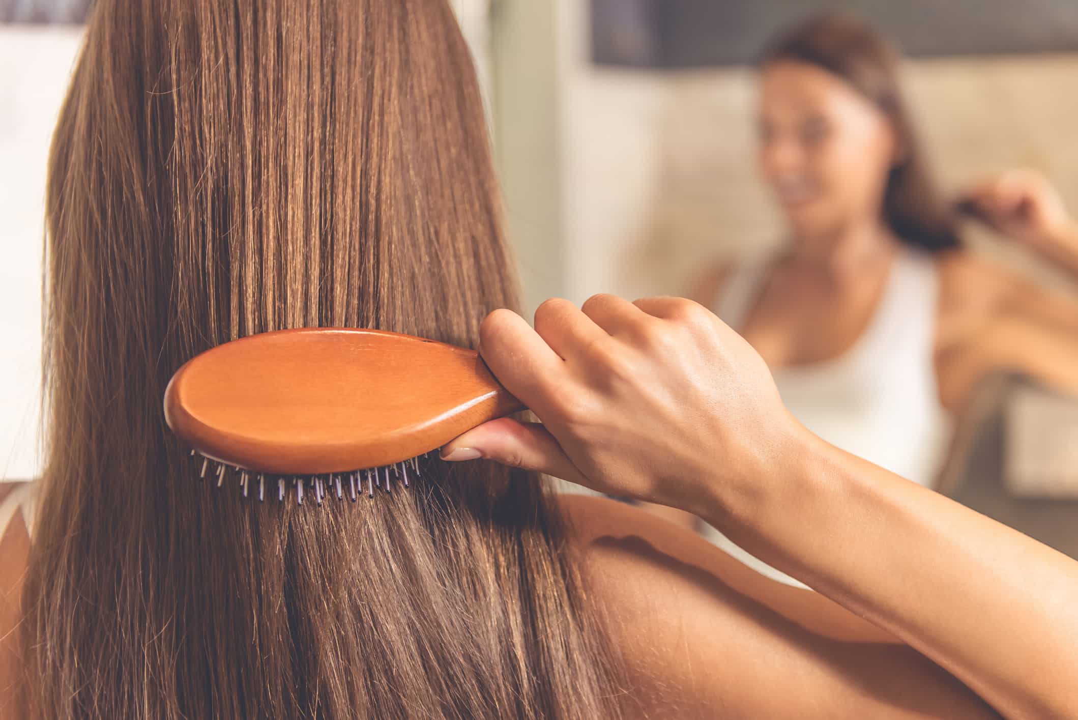  Mulher penteando cabelo castanho longo no espelho