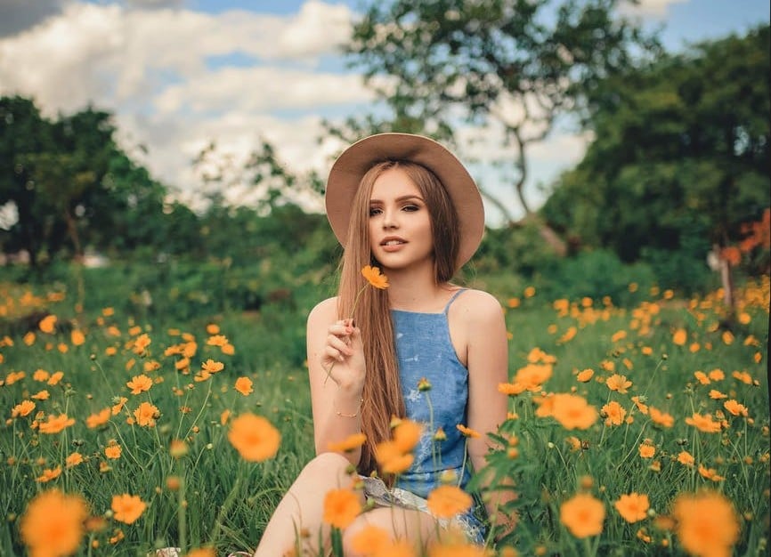  Modelo no jardim de flores com chapéu mostra todo seu charme com o cabelo liso grande