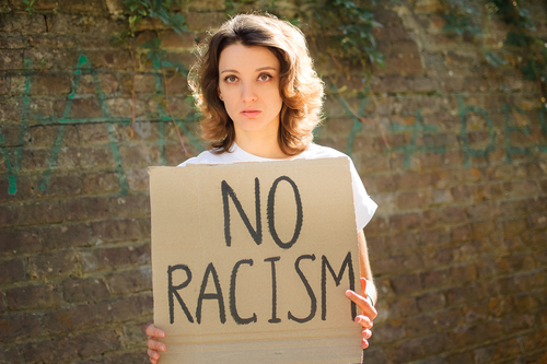  Mulher branca, segurando uma placa em protesto contra o Racismo Reverso