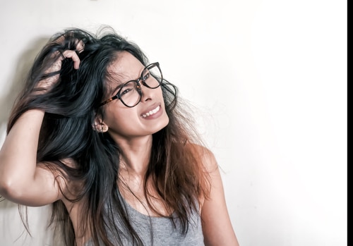  Mulher com caspa coçando o cabelo