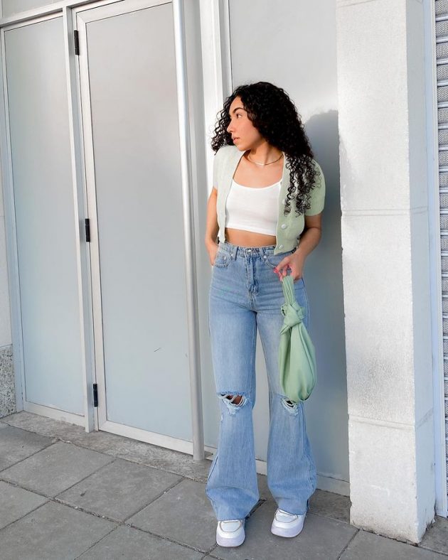 Moça de calça jeans clara e blusa branca.