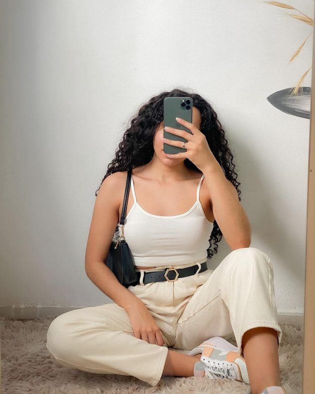 Moça com blusa branca e calça jeans bege.