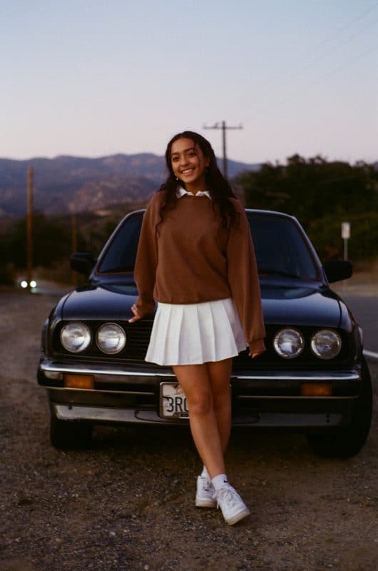 Uma moça com minissaia branco, um estilo anos 2000.
