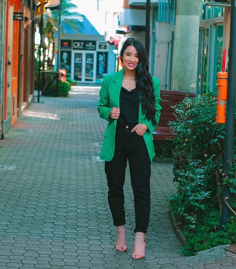  Mulher branca de cabelo preto, longo e liso, com look de inverno (conjunto preto com blazer verde)