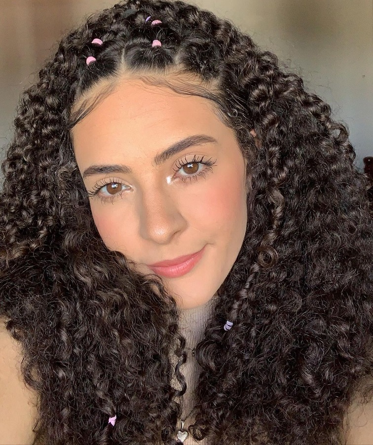  Mulher jovem de cabelo cacheado com penteado com liguinha e baby hair