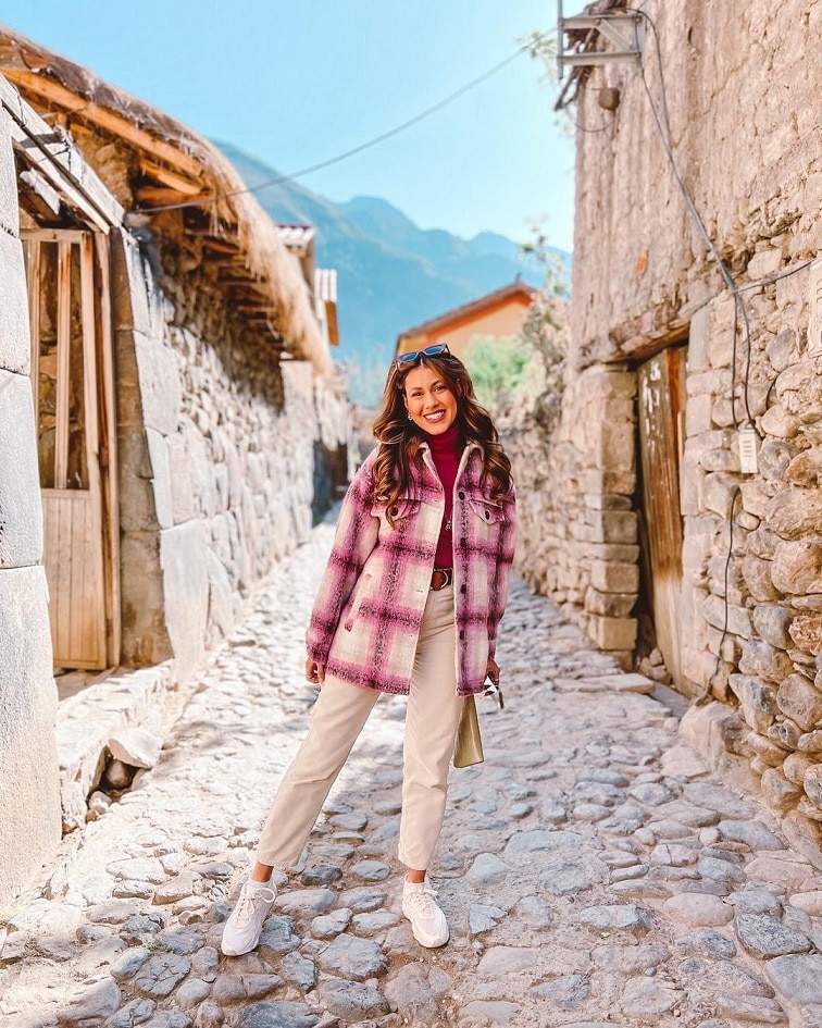  Mulher com tênis branco, calça de alfaiataria bege, blusa vermelha e sobretudo com estampa xadrez