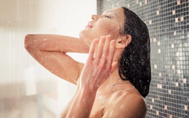 Mulher branca com o couro cabeludo ressecado, lavando o cabelo liso preto no chuveiro