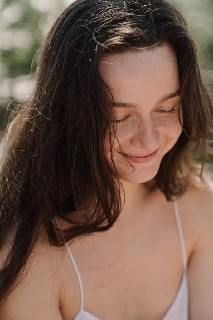 mulher branca sorrindo com olhos fechados