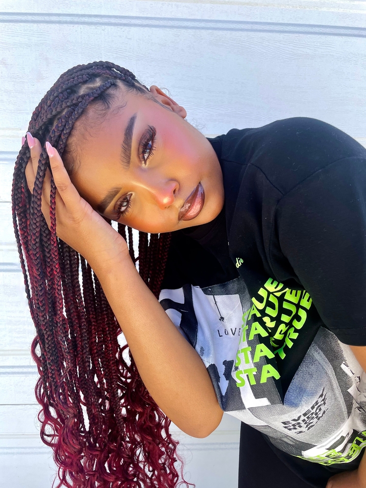 Mulher com box braids com cachos nas pontas, na cor marsala, e baby hair