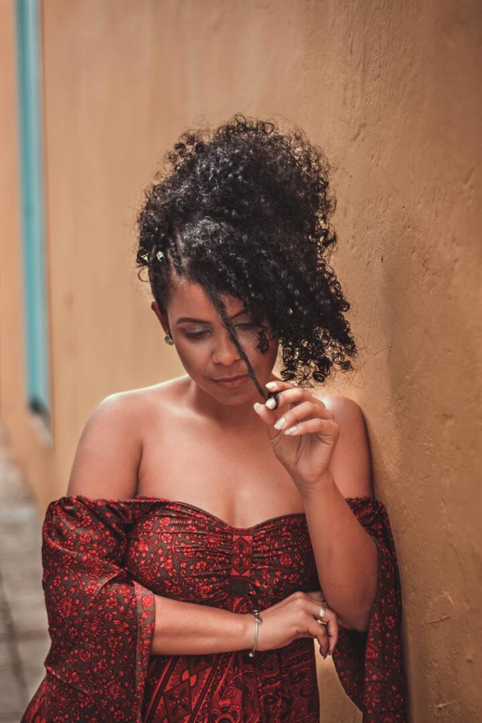 Mulher de cabelo cacheado com penteado coque abacaxi com franja