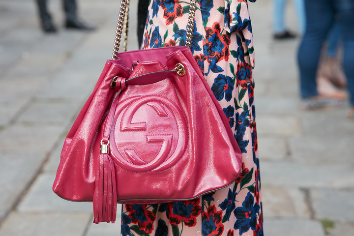 mulher segurando bolsa cor magenta