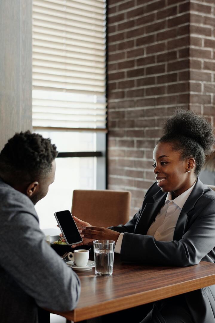 Profissionais negros em reunião de negócios com celular e café