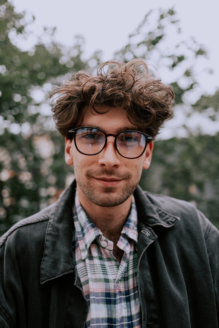  homem branco usando oculos de grau com cabelos finos encaracolados